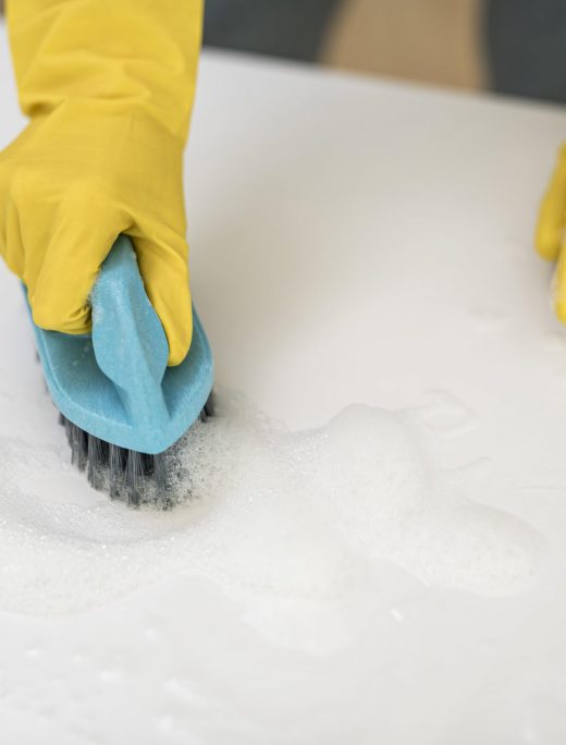 high angle woman with cleaning gloves using brush